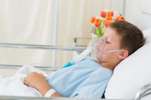 Niño enfermo en cama hospitalaria con respirador